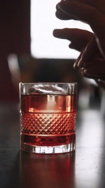 Dikey video. İçki servisi. Citrus kokteyli. Barmen eli portakal suyu serpiyor. Geniş camların kenarlarını siliyor. Parlak aromatik ferahlatıcı aperatif.