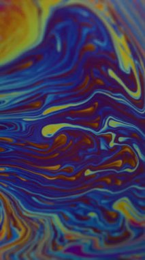 Dikey video. Renkli sıvı. Benzin deseni. Odaklanamayan mavi mor parlak mürekkep sıvısı soyut akrilik sanat arka planına dökülüyor..