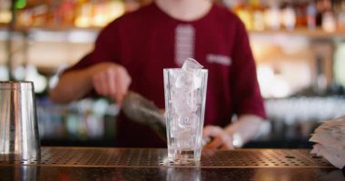 Kokteyl barı. Soğuk içecek hazırlanıyor. Barmen metal karıştırıcıya buz ekliyor. Profesyonel barmen kafeteryada canlandırıcı içecek yapıyor..