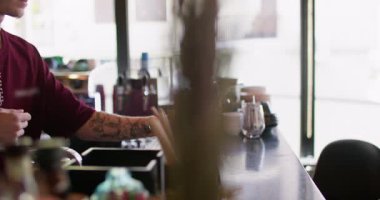 Barmen içki hazırlıyor. Kokteyl barı. Büyük bardağa kırmızı buzlu saman ekleyen adam. Meyhane tezgahında aromalı nane likörü..