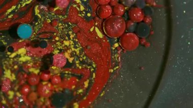 Mürekkep akışı. Köpükler karışır. Soyut bokeh arkaplan üzerinde yüzen yağ emülsiyon su dokusu etrafında sönmüş kırmızı mor renk simleri.