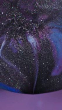 Dikey video. Odaklanamayan parlak emülsiyon. Prizma sıvısı. Küre merceğinin soyut arka planında siyah parıldayan sıvı sızıntısı var. Mor mavi boya kozmik renk karışımı.