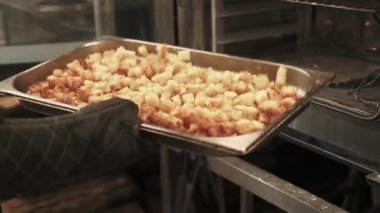 Fırın iş akışı. Kurutulmuş ekmek. Aşçı elleri fırın eldiveni ile büyük metal restoran sobası örtüsüne altın ekmek parçaları karıştırıyor..