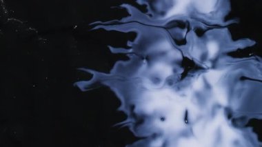Mürekkep sıvısı. Görüntü serpiştirme sanatı. Odaklanmamış gümüş rengi su dokusu soyut akrilik koyu siyah arkaplan üzerinde parlak sıvı akışı.