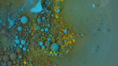 Boya akışı. Köpüklü yağ mürekkebi. Soyut akrilik arka planda çözünmüş sarı mor renkli simli baloncuk karışık su çemberi.