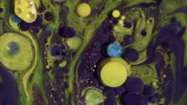 Boya parçacıkları. Mürekkep kabarcıkları. Soyut sanat arka planında parlayan sarı mavi parıltılı su yağ akış çemberinin etrafında parlıyor.