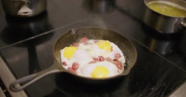 Yemek pişirmek. Kızartma tabağı. Siyah tavada yumurta sarısı kes. Profesyonel mutfakta dumanı üstünde sıcak bir yemek hazırlıyorum..