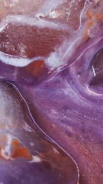 Dikey video. Eriyen sıvı. Buz dokusu. Bulanık mor turuncu mavi renkli parlak mürekkep soyut donmuş akrilik arka planda yüzen beyaz su akışı.