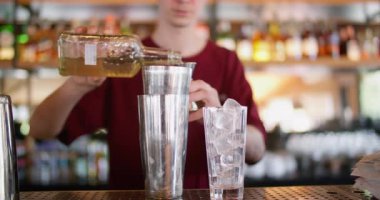 Kafe içkisi. Jigger kullanarak. Barmen bardağa alkollü sıvı dolduruyor. Buzlu taze kokteyl için aroma şurubu ölçülüyor.