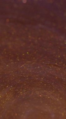 Dikey video. Boya dökülmüş. Akrilik girdap dokusu. Odaklanmamış sarı mor renkli simler soyut arkaplanda akıyor..