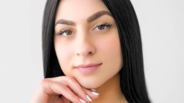 Yüzü pürüzsüz. Sağlıklı bir parıltı. Genç bir kadın çeneye dokunuyor. Doğal sağlığını gösteren sakin bir kız beyaza izole edilmiş güzellik makyajı..