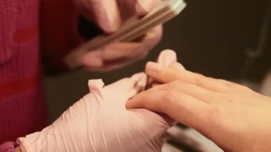 El manikürü. Tırnak cilası çıkarma. Koruyucu eldivenli profesyonel kadın manikürcü müşteriler güzellik hizmetleri sırasında Emery board pamuk pedi kullanıyorlar..