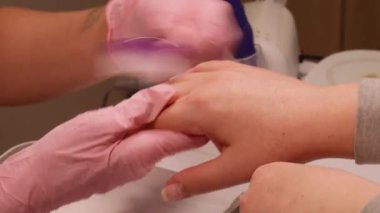 Temizleme prosedürü. Profesyonel spa terapisi. Pembe tıp eldivenli kadın teknisyen fırça kullanıyor müşterileri tırnak sürecine hazırlıyor..