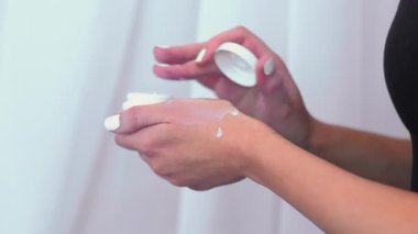 Kol derisi. Dermatoloji rutini. Beyaz merhem sürerken elinde kavanoz kremi tutan manikürlü kadın elleri. Günlük sağlıklı terapi masajı.