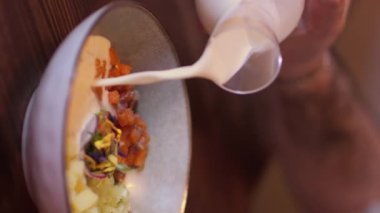 Dikey video. Sağlıklı yiyecekler. Beslenme karışımı. Adam kefir ile sebze kırmızı balık yemeği servis ediyor. Lezzetli geleneksel doğranmış malzemeler için sıvı krema sosu..