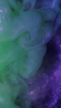 Dikey video. Dönen sıvı. Arkaplanı boya. Odaklanamayan sarı neon rengi duman simli gökkuşağı koyu siyah soyutlama üzerine yayılan sıvı..