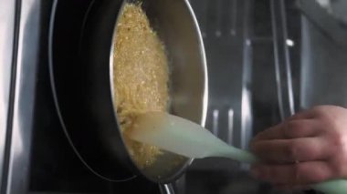 Dikey video. Heyecan verici bir yemek. Sıcak yemek pişirmek. Şef, spatula karışımı metal tavada pilav kaynatıyor. El yapımı otantik paella tarifi..
