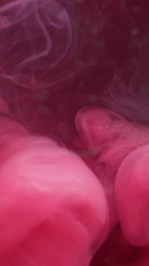 Dikey video. Parlak mürekkep sıçraması. Duman bulutu dokusu. Odaklanamayan pembe parıldayan buhar dalgası soyut sanat arkaplanı yayıyor..