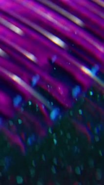 Dikey video. Bulanık ışık parlıyor. Parıltılı soyutlama. Odaklanmamış mor floresan görsel neon lens koyu siyah ışıklı arka planda hareket eden optik işaret fişeği.