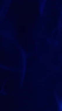 Dikey video. Arkaplanı boya. Duman akışı. Odaklanmamış mavi neon rengi buhar suyu deseni pigmenti soyut koyu siyah soyutlama üzerinde hareket ediyor.