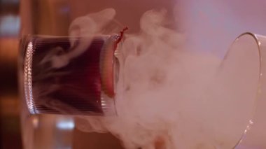Dikey video. Barmen servisi. Kokteyl dumanı. Cam kapaklı, alkollü içecekten çıkartan soğuk duman. Bar tezgahında nefis aperatif yapmak.