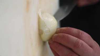 Dikey video. Soğan doğruyorum. Sebze dilimleme. Şef elleri dikkatlice taze, taze, baharatlı organik malzemeyi mutfak masasında bıçakla kesiyor..