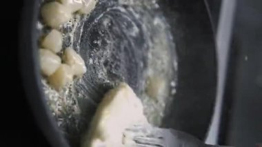 Dikey video. İstiridye hazırlıyorum. Deniz tarağı pişiriyorum. Siyah sıcak tavada kızaran soyulmuş protein bileşenleri. Şef lezzetli soslar için tereyağı ekliyor..