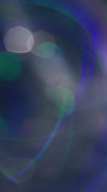 Dikey video. Optik ışıltı. Bokeh çemberi. Odaksız mavi turuncu renkli parlak mercek soyut bulanık sanat arka planında hareket ediyor.