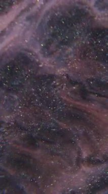 Dikey video. Pırıl pırıl. Sıçrama sıvısı. Soyut sanat arkaplanındaki pembemsi mavi boya kimyasal pigment parçacıkları.