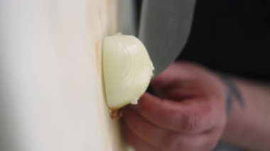 Dikey video. Aşçı kesimi. Malzeme doğruyorum. Mutfak tahtasındaki bıçaklı beyaz soğanı ustalıkla hazırlıyorum. Çiğ taze vejetaryen mutfağı..