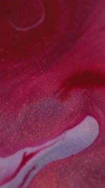 Dikey video. Işıldayan su sıçraması. Parıltılı boya döküldü. Odaklanmamış kırmızı mavi renk parlak damlalar desen sıvı karışım akışı soyut sanat arka planı.