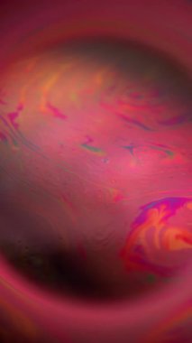 Dikey video. Sabun temizlenmiş baloncuk. Renkli boya gezegeni. Siyah çerçevede yuvarlak mercek karışımı boya akışı. Kırmızı pembe gece soyut sıcak küre.