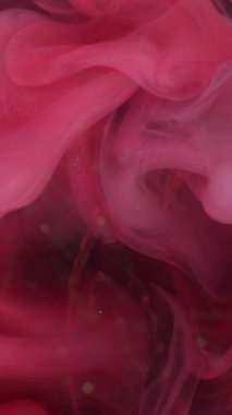 Dikey video. Duman yüzüyor. Mürekkep karışımı. Odaklanmamış pembe ışıldayan parçacıklar buhar dalgası akışı soyut sanat arkaplanını harmanlıyor.