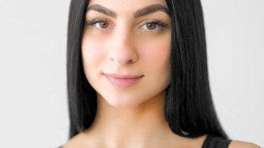 Kadın güzelliği. Doğal cazibe. Uzun siyah kilitleri olan yumuşak, genç bir kadın, huzurlu bir ifade. Cilt kılları beyaza izole edilmiş..