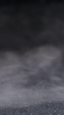 Dikey video. Sis akışı. Boya dumanı. Odaklanmamış beyaz su buharı sıvı doku parçacıkları soyut buhar siyah arkaplan üzerinde yayılıyor.