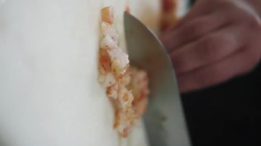 Dikey video. Karides hazırlanıyor. Deniz ürünleri doğramak. Şefin elleri gurme yemeği için karides eti pişiriyor. Beyaz fotokopi alanında sağlıklı yemek için suşi malzemeleri.