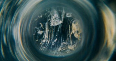 Duman mürekkebi bulanıklığı. Tünel merceği. Sarı gri renkli dumanlı dumanlı dumanlı sıvı. Soyut siyah arkaplanda yuvarlak prizmaya renk damlası döküldü.