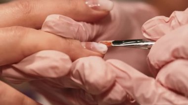 Tırnak cilası. Tırnaklarına dikkat et. Kadın, koruyucu lateks eldivenli güzellik uzmanı tarafından profesyonel el tedavisi görüyor..