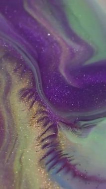 Dikey video. Renk karışımı. Parlak doku. Odaklanmamış mor yeşil boya soyut arkaplana yayılan parlak parçacıklar..