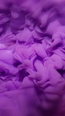 Dikey video. Renk karışımı. Mürekkep arkaplanı. Odaklanmamış pembe parlak duman akrilik soyutlamaya yayılan parlak leylak sıvısı sıçratır.