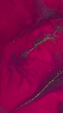 Dikey video. Sıvı dökülmesi. Parıldayan mürekkep. Sönük sarı pembe renkli parlak boya soyut neon bokeh arka planına yayılıyor..