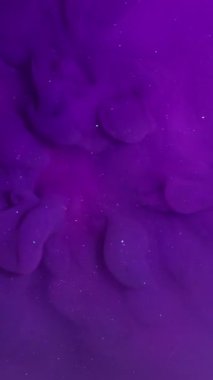 Dikey video. Akan mürekkep. Sıvı sıçraması. Odaklanmamış mor neon rengi soyut pembe arka planda yüzen ışıltılı nemli doku.