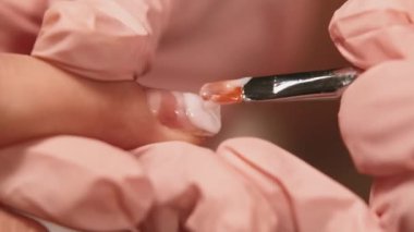 Çivi levhası hizalanıyor. Salon tedavisi. Güzel kadın koruyucu pembe lateks eldivenler içinde müşterilerin parmaklarını akrilik cila tutarak kaplıyor..