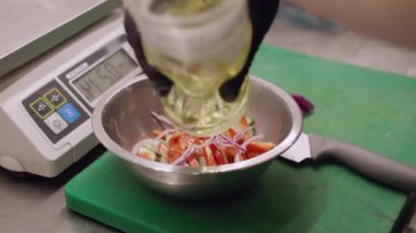Mutfak süreci. Beslenme yemeği. Şefin eli metal kasede sağlıklı taze salata pişiriyor. Domates salatalıklı soğan yağlı lezzetli diyet yemekleri..
