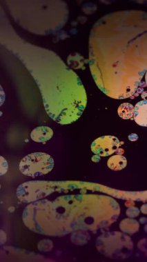 Dikey video. Benzin deseni. Kaotik balon bulanıklığı. Suyun üzerinde yüzen boya damlaları. Fizz ışıltısı akışı odaklanmış sanat siyah arkaplanı.