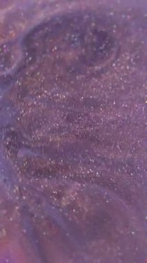 Dikey video. Sıçrama dokusu. Boya karışımı. Odaklanamayan mor renkli köpükler akan su soyut akrilik sanat arka planına yayılıyor..