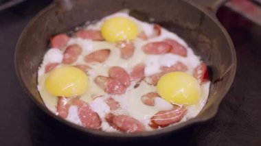 Akşam yemeğini hazırlıyorum. Kızarmış yumurta. Sosis dilimleri kaynayan buhar yağında kızartılıyor. Siyah elektrikli ocakta lezzetli yemekler pişirmek..