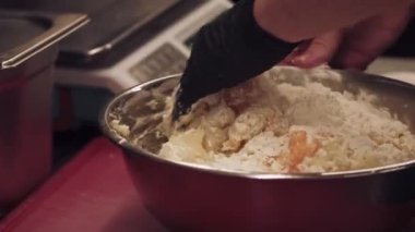 Yemek pişirme süreci. Hamur karıştırıyorum. Profesyonel şef eldiven giymiş, metal kasede ıslak un yumurtası yoğuruyor. Hamur işi tekniği.