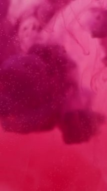 Dikey video. Duman sıvısı. Boya karışımı. Renk karışımı girdaplı sanat suyu damlası. Odaklanamayan pigment dağılımı. Soyut pembe sıvı doku arkaplanı.