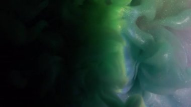 Mürekkep karışımı. Renkli bulut dokusu. Odaklanmamış mavi mor sıçrama gökkuşağı simli su soyut koyu siyah arka planda yayılıyor..